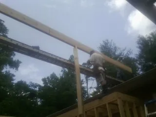 Carpenter setting a ridge beam over a new addition frame — Ice Dam Removal by Roofing Brothers in Byfield