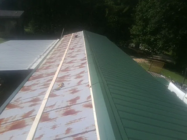 Old rusted panels beside newly installed green metal roofing — Wind Damage Roof Repair by Roofing Brothers in Byfield