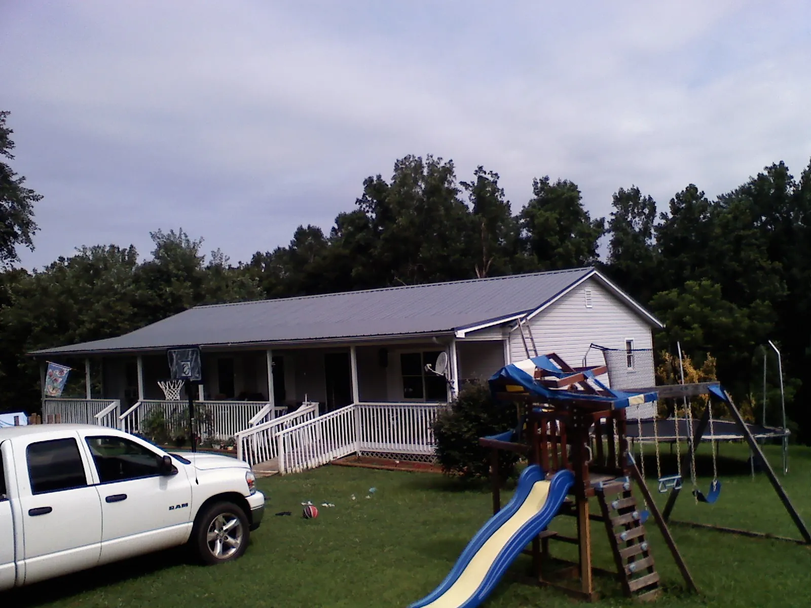 Dark metal roof on a country home with a full length front porch in Byfield