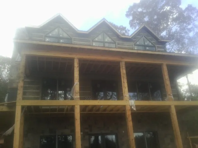 Dormers and porch framing on a large log home under construction — Roof Coating work by our crew in Byfield
