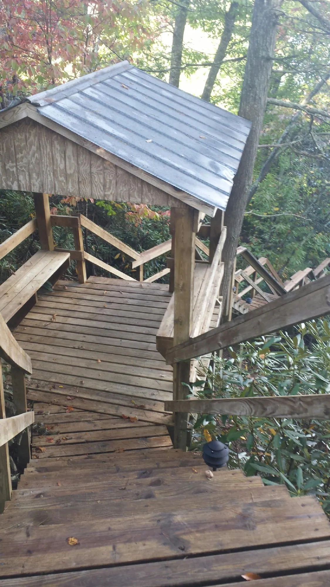 Metal roofed shelter over wooden steps on a wooded walkway — Skylight Repair & Installation work by our crew in Byfield