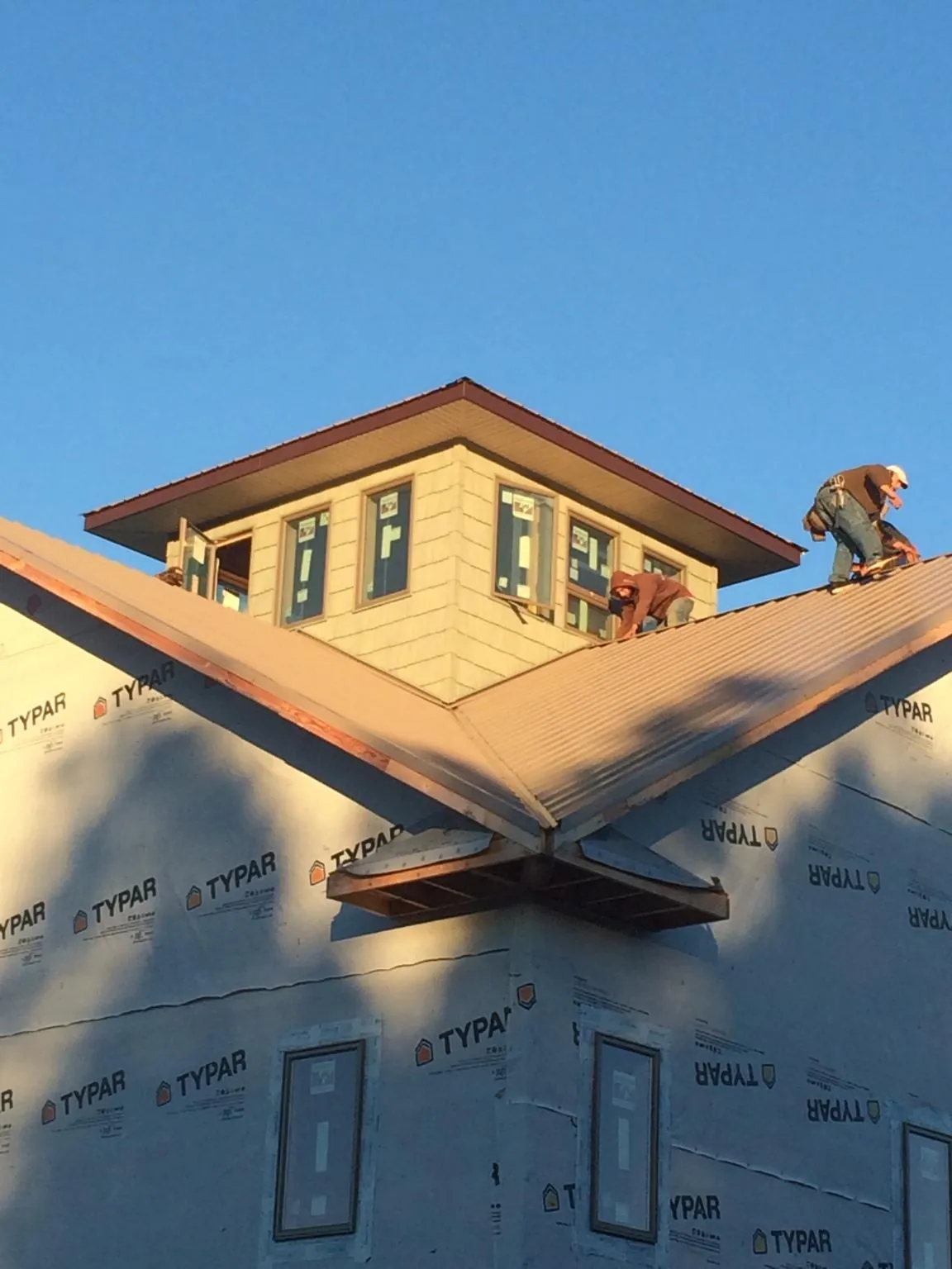 Roofers working around a rooftop cupola on a new metal roof at sunset — Roof Waterproofing in Byfield by Roofing Brothers